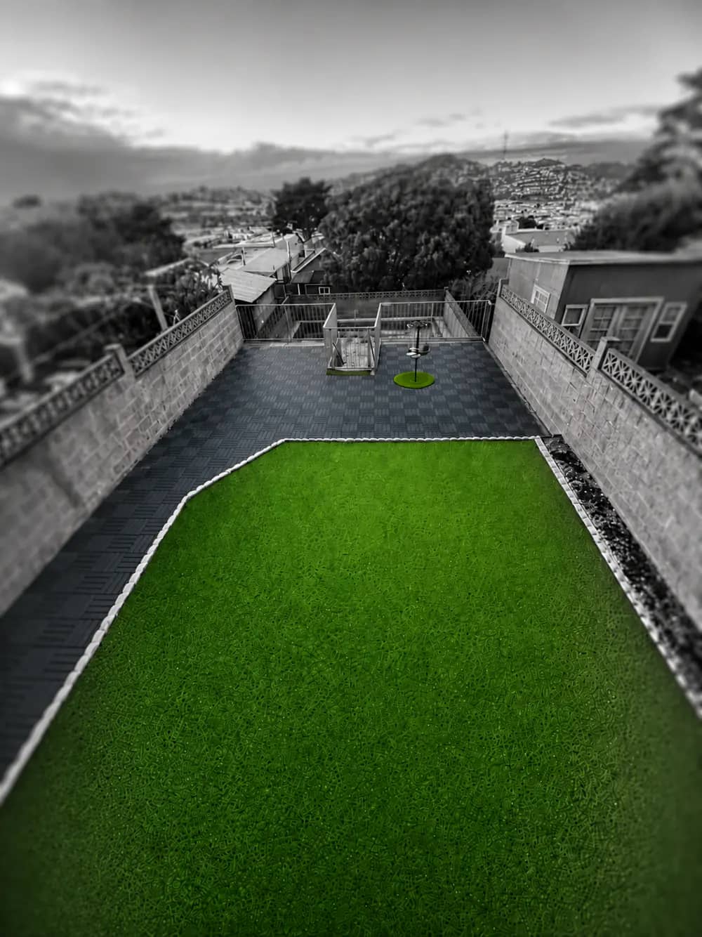 Overhead view of the fenced yard with green turf and San Francisco hills beyond